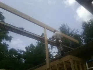 Carpenter setting a ridge beam over a new addition frame — Ice Dam Removal by Roofing Brothers in Lamoure