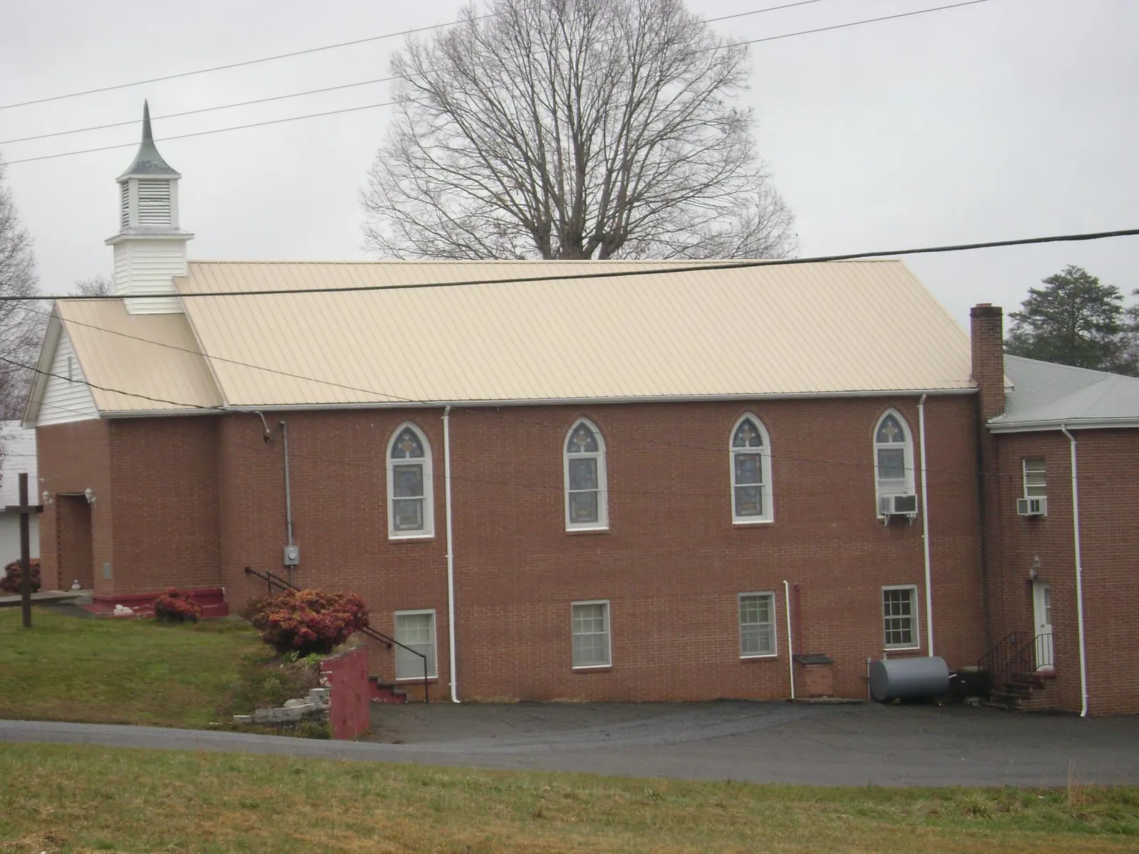 New tan metal roof on a brick church with a white steeple in Lamoure