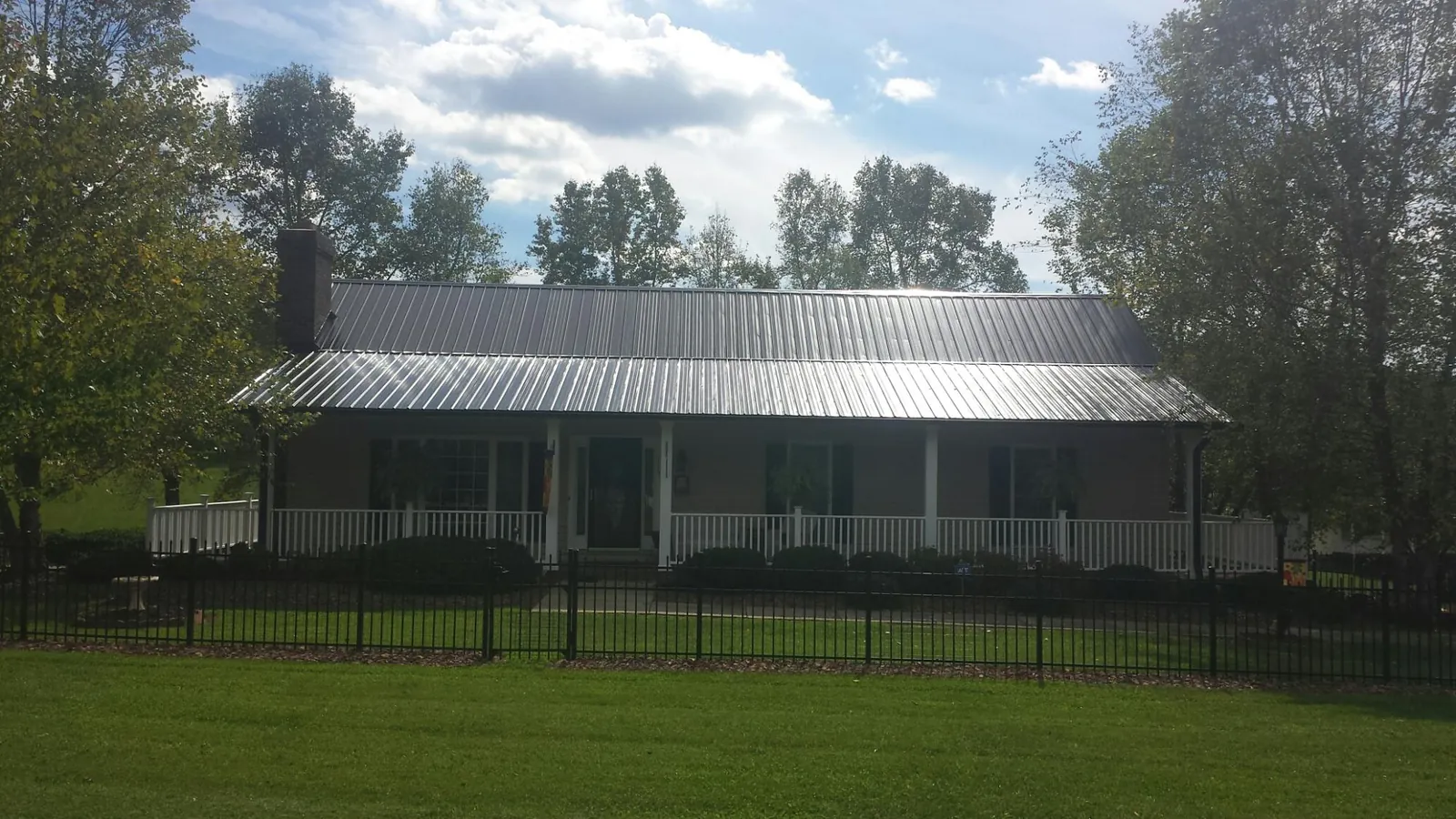 Gray metal roof on a brick ranch with a full width front porch — Gutter Guard Installation work by our crew in Lamoure
