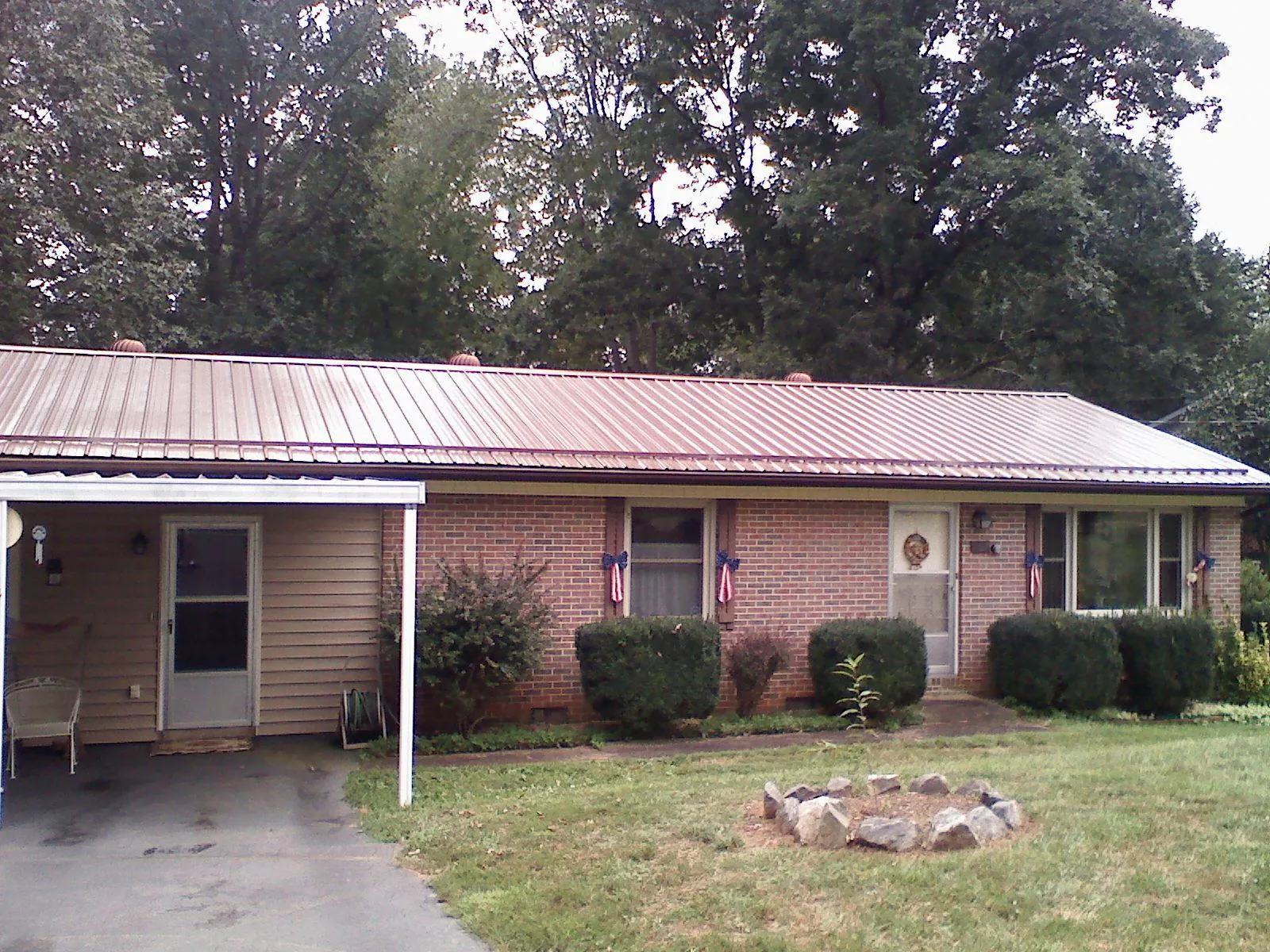 Bronze metal roof and carport on a brick ranch home — Roof Repair work by our crew in Lamoure
